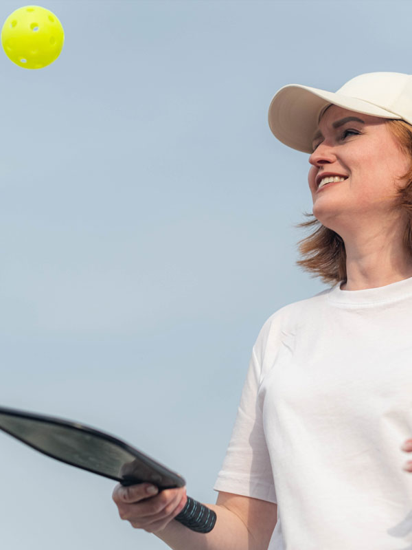 Middle Aged Woman Playing Pickleball Game Over Blue Sky, Pickleball Yellow Ball With Paddle, Outdoor Sport Leisure Activity.